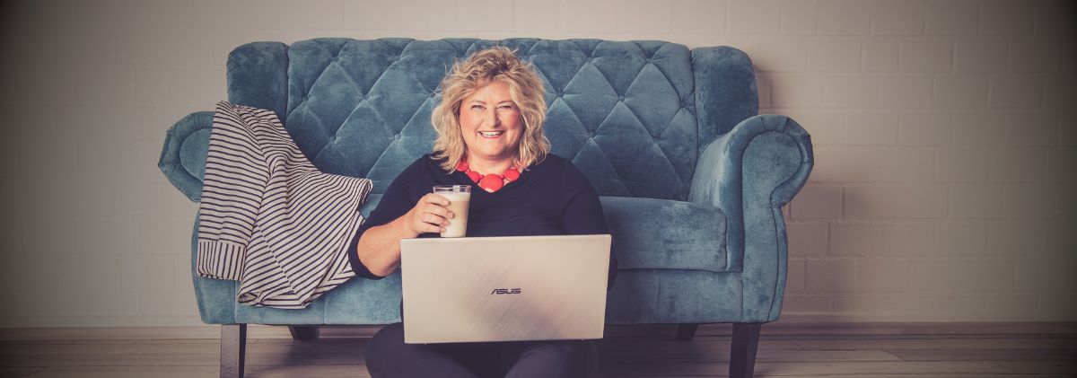 Birgit Gosejacob sitting on the floor in front of a sofa writing on a laptop