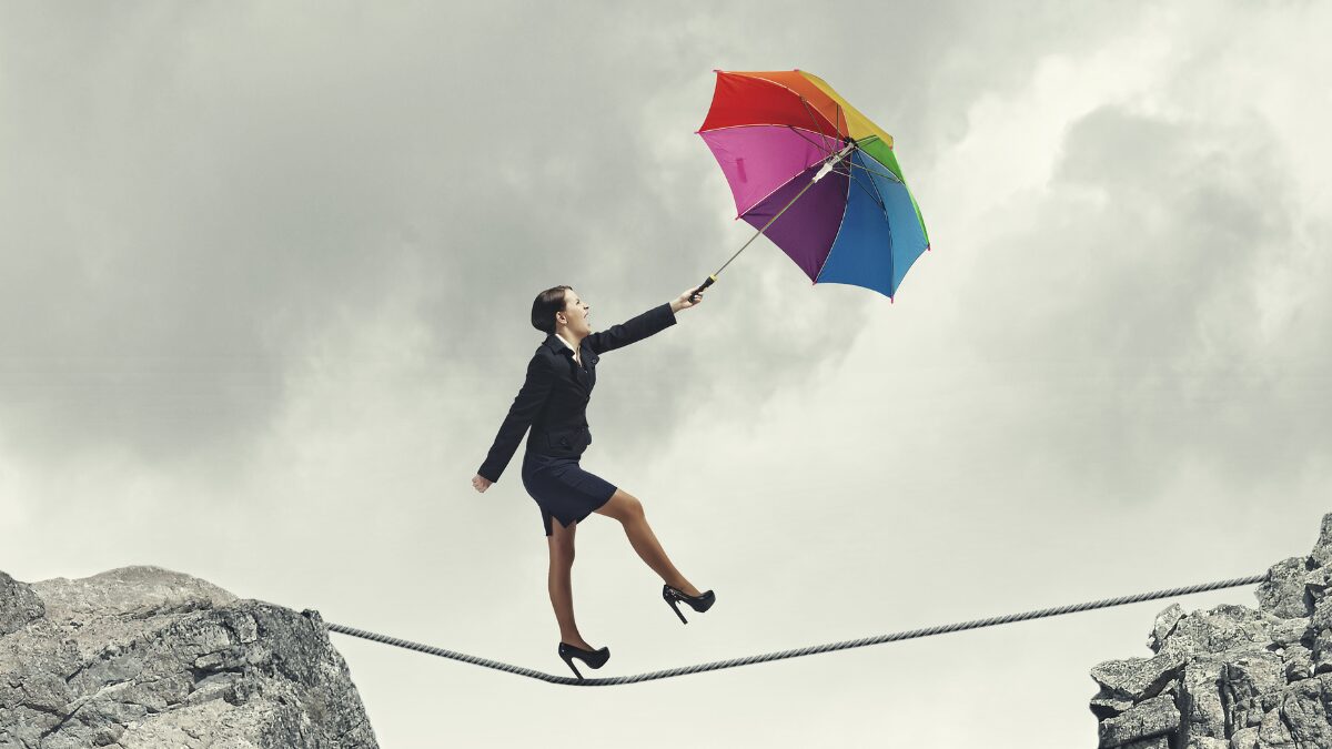 Symbolic for basic essential skills: A woman in business suit and high heels dancing on a rope drawn by a colorful umbrella she holds up into the wind